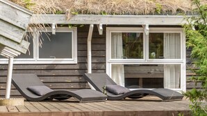 A wooden deck with two lounge chairs and a thatched roof. - "Alfi" - 150m from the sea by Interhome (Sæby)