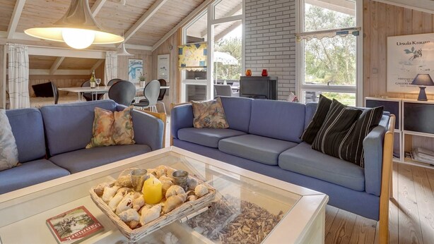 A cozy living room with a blue sofa, a glass coffee table with decorative items, and a fireplace. - "Alfi" - 150m from the sea by Interhome (Sæby)