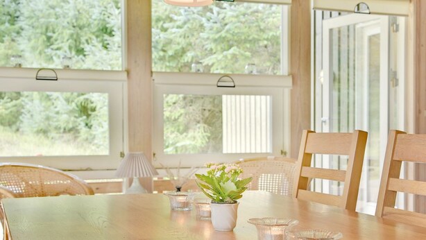 Ein Essbereich mit einem Holztisch, Stühlen, einem Blumentopf und kleinen Glaswindlichtern.