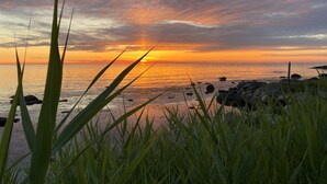 A sunset over a beach with rocks and grass in the foreground. - "Scarlet" - 5m from the sea by Interhome (Hasle)