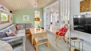 A modern living room with a sofa, a dining table, a red chair, and a TV. - "Anline" - 900m to the fjord by Interhome (Tarm)