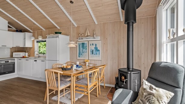 Un intérieur moderne comprenant un coin repas, une cuisine et un poêle à bois.