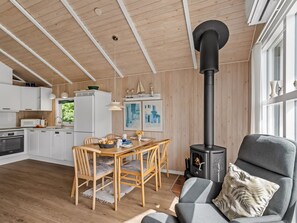 Un intérieur moderne comprenant un coin repas, une cuisine et un poêle à bois.