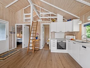 Une cuisine moderne avec des meubles blancs, un four encastré et une échelle en bois.