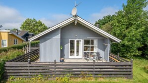 Un petit bâtiment d’un seul étage, doté d’un toit en pente, d’une antenne parabolique et d’une terrasse avec des sièges extérieurs.