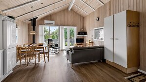 A modern kitchen with wooden flooring, a dining area with a table and chairs, a sofa, and a large white cabinet.