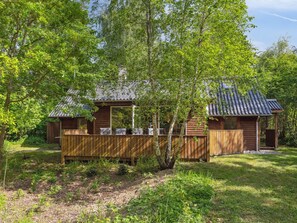 Une cabane en bois dotée d’une terrasse, entourée d’arbres.