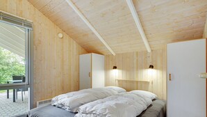 A bedroom with a wooden ceiling, a bed with white bedding, a grey blanket, and a window overlooking greenery. - "Danna" - 850m to the fjord by Interhome (Hemmet)