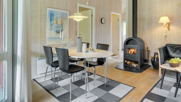 A cozy living room with a central fireplace, a dining area with chairs and a table, and a large window providing natural light. - "Danna" - 850m to the fjord by Interhome (Hemmet)