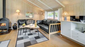 A cozy living room with a fireplace, a sofa, a coffee table, and a kitchen area with cabinets and a countertop. - "Danna" - 850m to the fjord by Interhome (Hemmet)