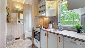 A modern kitchen with wooden walls, white cabinets, a built-in oven, and a window with a view of greenery. - "Danna" - 850m to the fjord by Interhome (Hemmet)