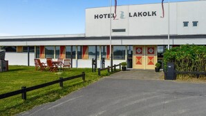 A modern building with the sign "HOTEL LAKOLK" and a flagpole with flags.