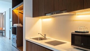 A modern kitchen with wooden cabinets, a stainless steel sink, and a microwave. - Zahoo house in Panorama Nha Trang  (Nha Trang)
