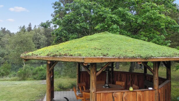 A wooden gazebo with a moss-covered roof, a bench, and a table with a lantern. - "Beatha" - 25km to the fjord by Interhome (Sønder Felding)