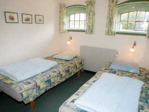 Ein Schlafsaalzimmer mit zwei Einzelbetten, einer Heizung und zwei Wandlampen.