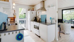 A modern kitchen with white cabinetry, a built-in oven, a sink, and a dining area with outdoor seating. - "Angantir" - 700m to the fjord by Interhome (Løgstør)