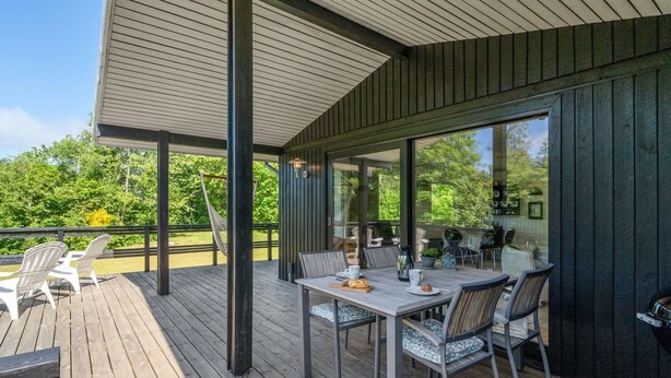 A covered outdoor patio with a table and chairs, a hammock, and a view of greenery. - "Angantir" - 700m to the fjord by Interhome (Løgstør)