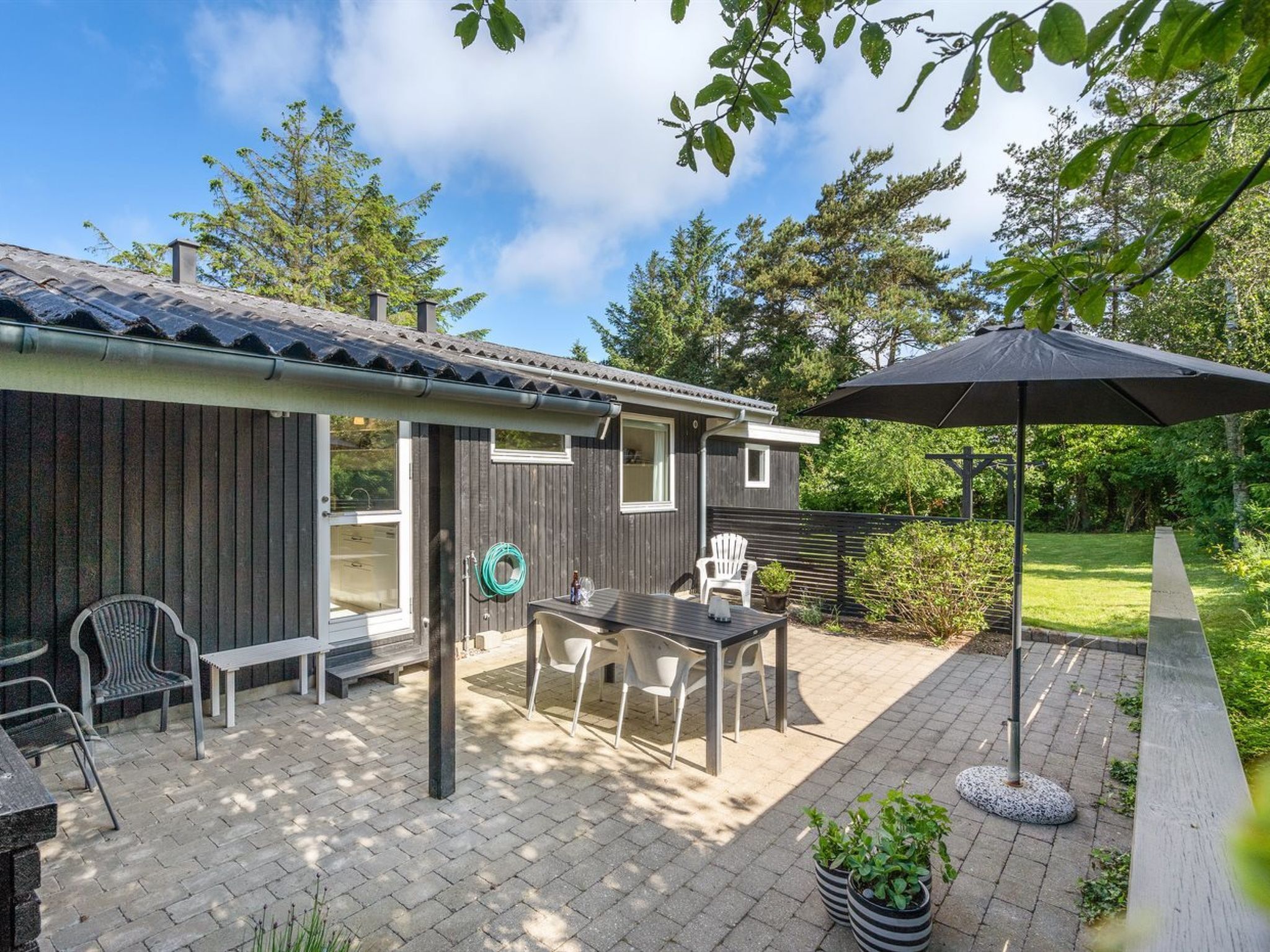 A patio area with a table and chairs, a bench, and a garden hose.