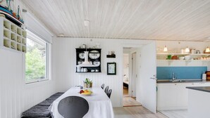 A modern kitchen with white cabinetry, a blue backsplash, and a dining area with a bench and table. - "Angantir" - 700m to the fjord by Interhome (Løgstør)