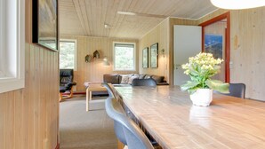 Ein geräumiger Wohnbereich mit Holzbalkendecke, einem Esstisch mit Stühlen, einer Couch und einem Couchtisch.