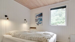 Ein Schlafzimmer mit einem Bett, einem Fenster, einem Wandregal und einem Poster.