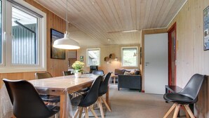 Ein modernes Interieur mit einem Holzespeisetisch, schwarzen Stühlen, einer Couch und einem großen Fenster.