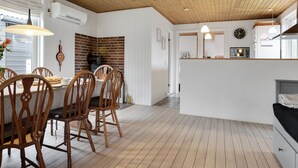 A modern kitchen with wooden flooring, a brick backsplash, and a central island with chairs.