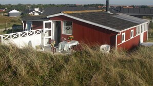 Un bâtiment rouge doté d’un balcon, entouré d’herbe haute.