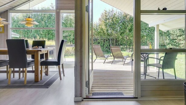 A modern interior with a dining area, a sliding glass door leading to an outdoor patio with chairs and a table. - "Wegher" - 650m from the sea by Interhome (Væggerløse)