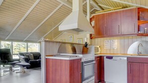 A compact kitchen with wooden cabinets, a built-in oven, and a microwave. - "Wegher" - 650m from the sea by Interhome (Væggerløse)