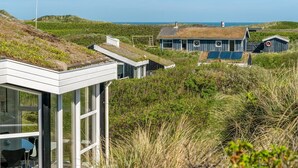 A modern building with a glass facade and a thatched roof structure in a coastal landscape. - "Swerting" - 230m from the sea by Interhome (Saltum)