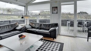 A modern, open-plan living area with a black leather sofa, a white coffee table, and a checkered rug. - "Swerting" - 230m from the sea by Interhome (Saltum)