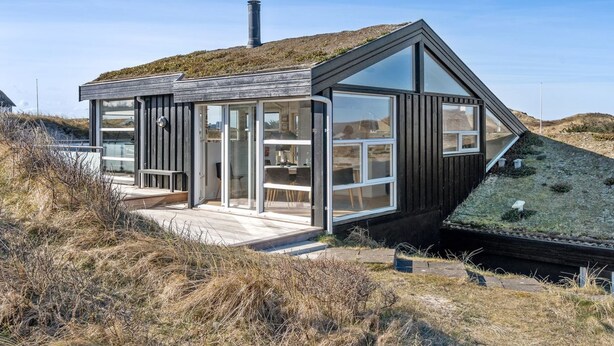 A modern house with a sloped roof, large glass windows, and a wooden deck. - "Swerting" - 230m from the sea by Interhome (Saltum)
