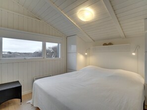 A bedroom with a large bed, a window with a view, a bench, and a ceiling light. - "Swerting" - 230m from the sea by Interhome (Saltum)