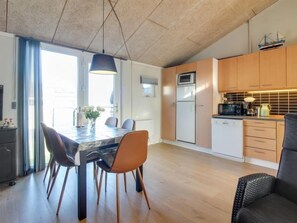 Enjoy a spacious living area with a dining table for four, comfortable seating, and a well-equipped kitchen with a microwave and refrigerator.