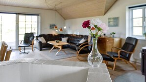 En rummelig opholdsstue med en moderne sofa, et sofabord og en vase med blomster.