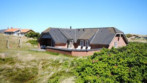 Et hus med skrå tag, murstensvægge og en lille veranda.
