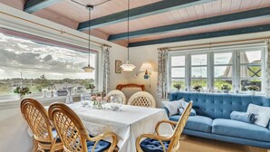 A dining area with a table set for four, surrounded by wicker chairs with blue cushions.