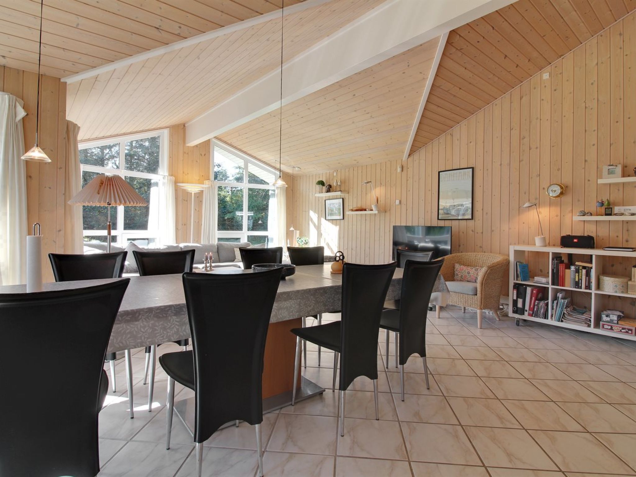 Une cuisine moderne avec un coin repas, des murs en bois et de grandes fenêtres.