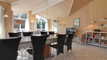 Une cuisine moderne avec un coin repas, des murs en bois et de grandes fenêtres.