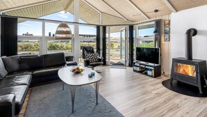A modern living room with a sofa, a coffee table, a TV, and a wood-burning stove. - "Sylta" -  from the sea by Interhome (Hvide Sande)
