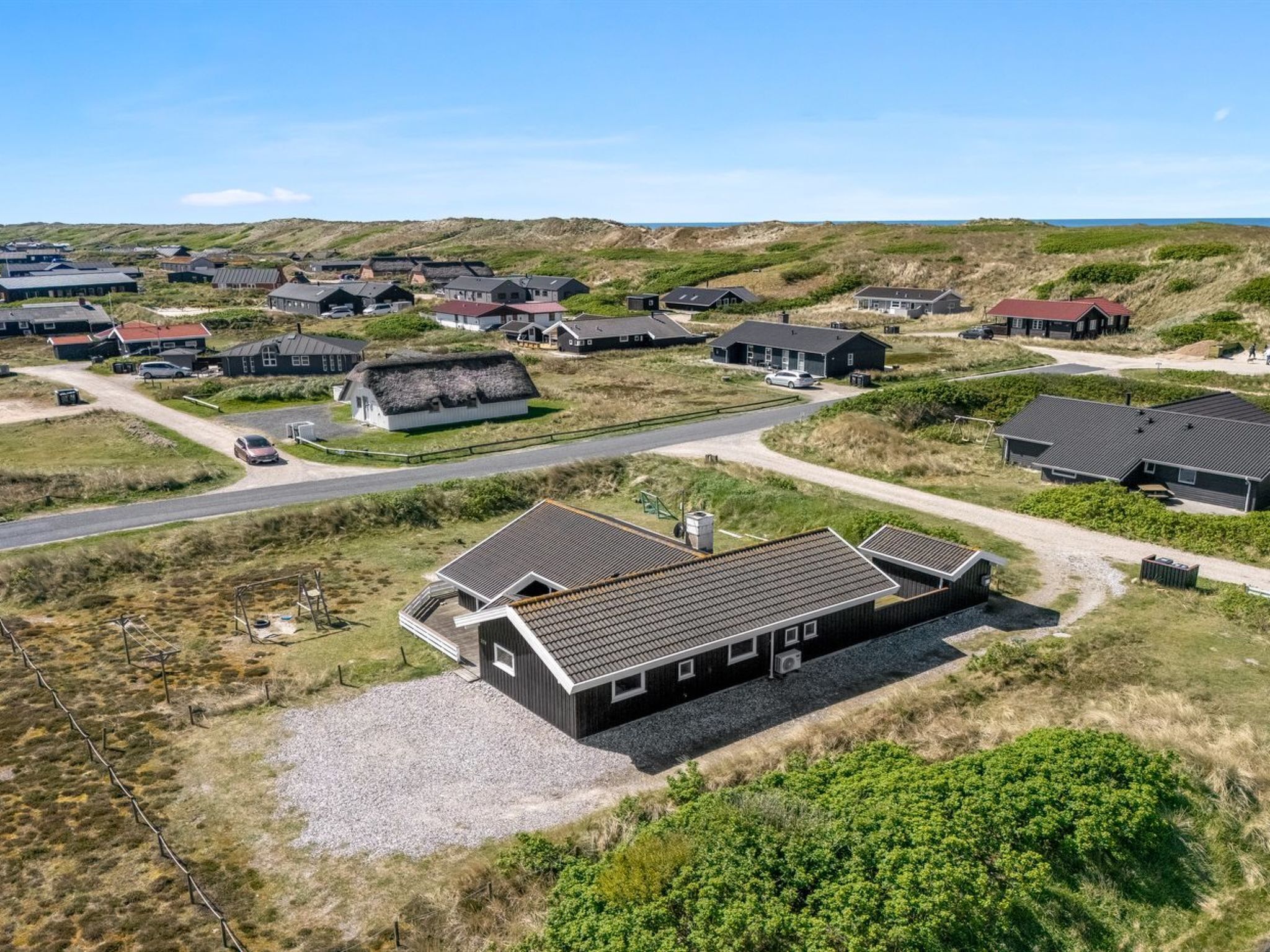 Un villaggio costiero con case tradizionali, una strada principale e una spiaggia sabbiosa.