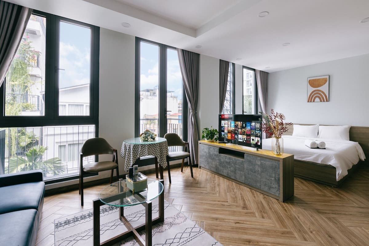 Une chambre d’hôtel moderne dotée d’une grande fenêtre, d’un canapé, d’une table à manger et d’un lit.
