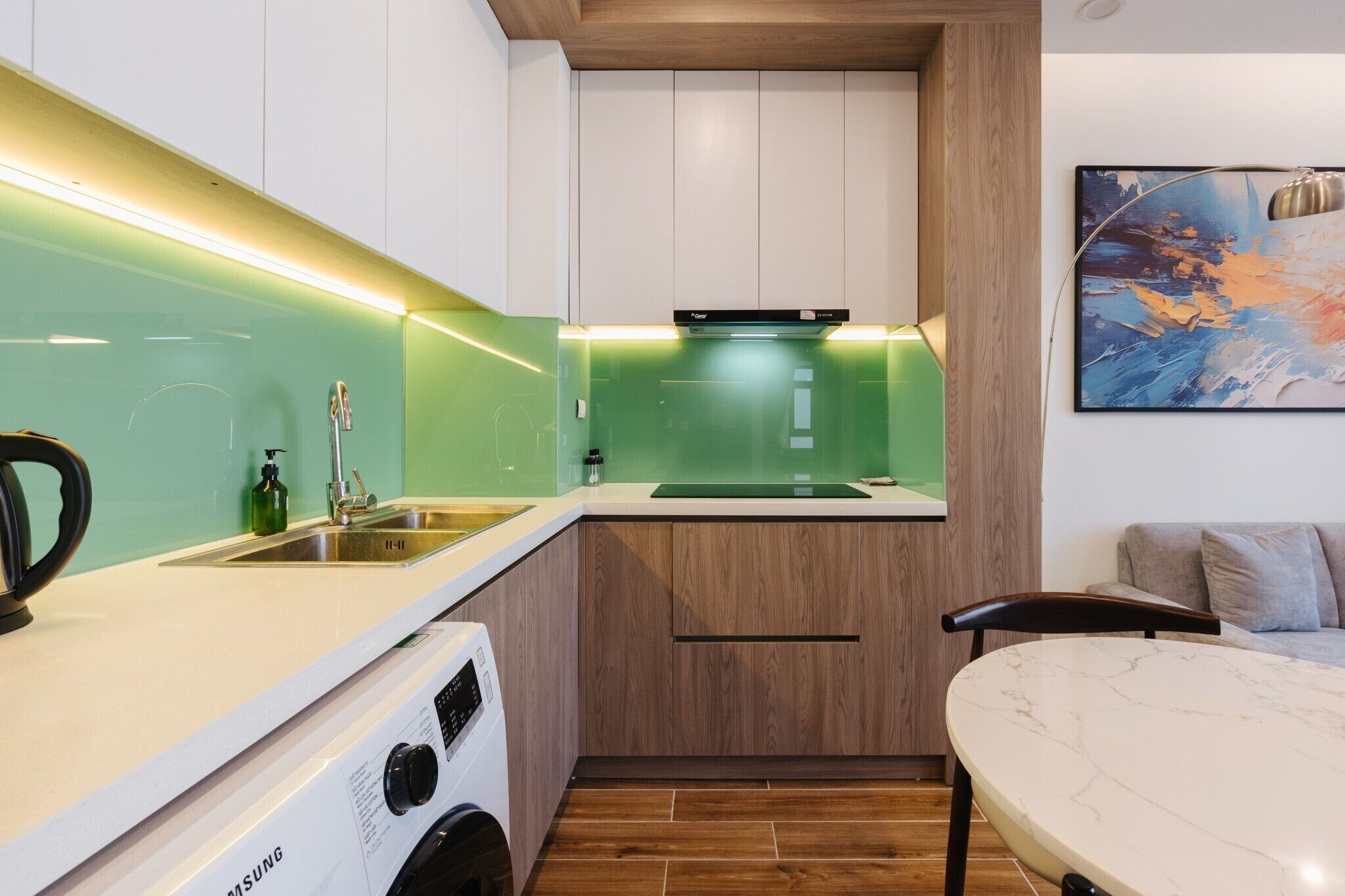 A compact kitchen with a built-in washer and dryer, a sink, and a wooden cabinet.