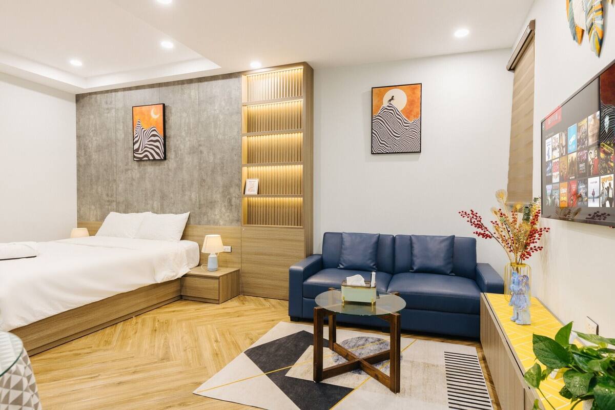 Une chambre d’hôtel moderne avec un lit, un canapé bleu, une petite table et un mur orné de tableaux.