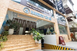 A hotel entrance with a sign for 'Westlake Emerald Suites' and 'Handico Tay Ho Street'.