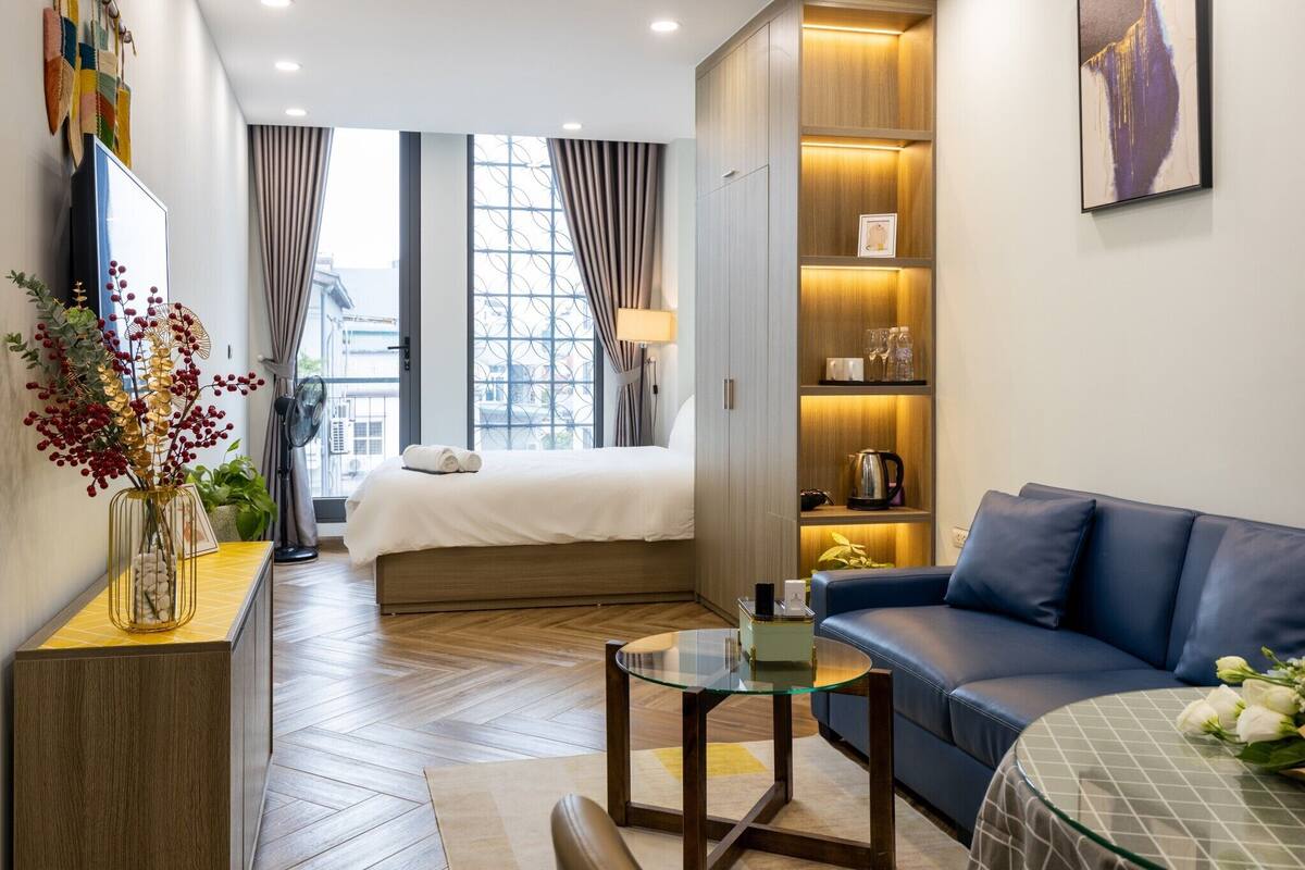Une chambre d’hôtel moderne équipée d’un lit, d’un canapé, d’une table basse en verre et d’une bibliothèque.