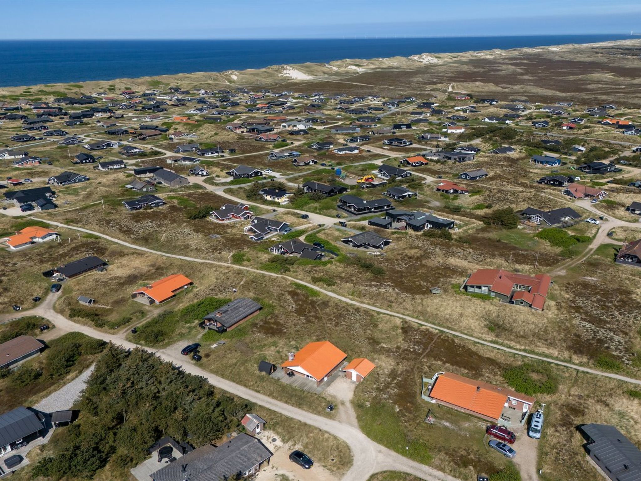 Vista aérea de una zona residencial con casas, carreteras y una costa.