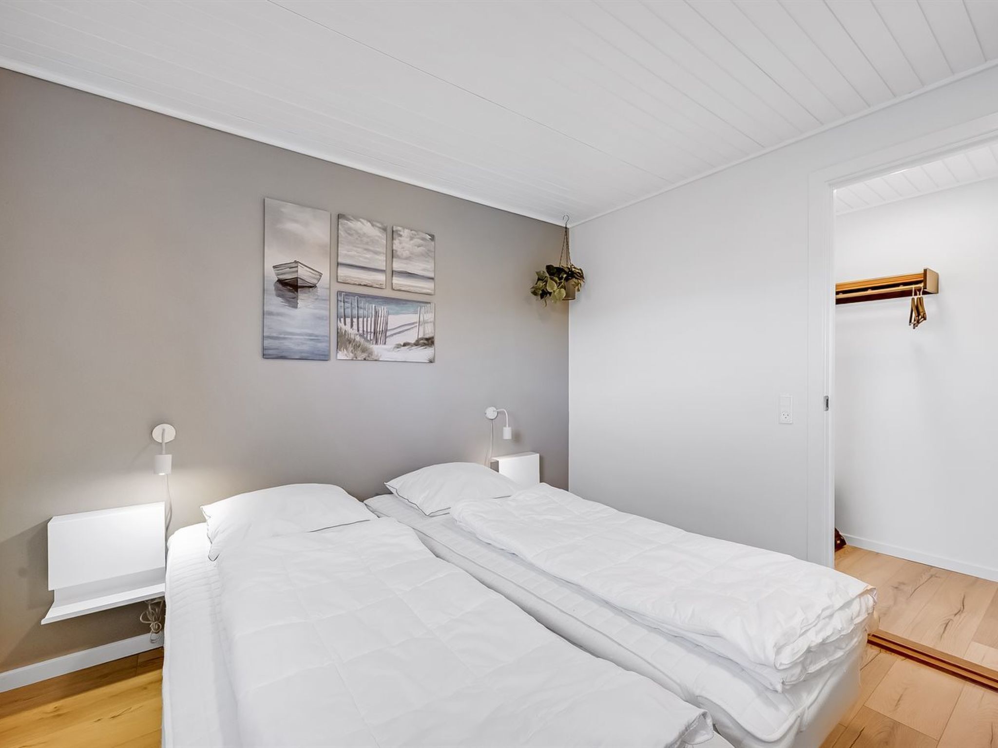 Ein Schlafzimmer mit zwei Einzelbetten, einem Nachttisch mit Lampe, einem Wandbild und einer Tür mit Handtuchhalter.