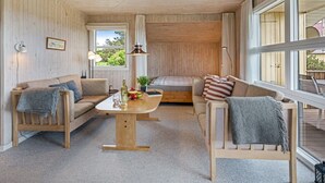 Una sala de estar acogedora con paredes y muebles de madera, un ventanal y vistas al exterior.